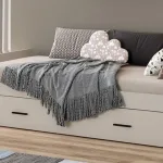 Cama nido Aura en beige con cajón inferior, cojines y manta, en un dormitorio