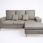 Sofá reversible chaiselongue Duque cemento, tapizado gris piedra claro con cojines y patas metálicas