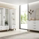 Salón con vitrinas y aparador Paris/Canarias blancos con encimera de madera junto a un ventanal