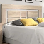 Ambiente con el cabecero Lara en madera y blanco tras una cama con cojines amarillos