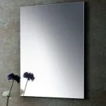 Espejo rectangular sin marco del mueble de baño Luque sobre pared de piedra oscura