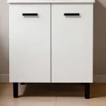 Detalle de las dos puertas blancas con tiradores negros y patas del mueble de baño Luque