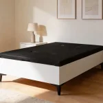 Canapé Rumba blanco con tapa negra en un dormitorio con mesita y lámpara